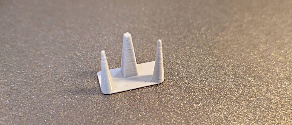 Ein perfekt gedrucktes Retraction-Testmodell aus grauem Extrudr PETG Filament ohne jegliches Stringing auf einem strukturierten Druckbett. 